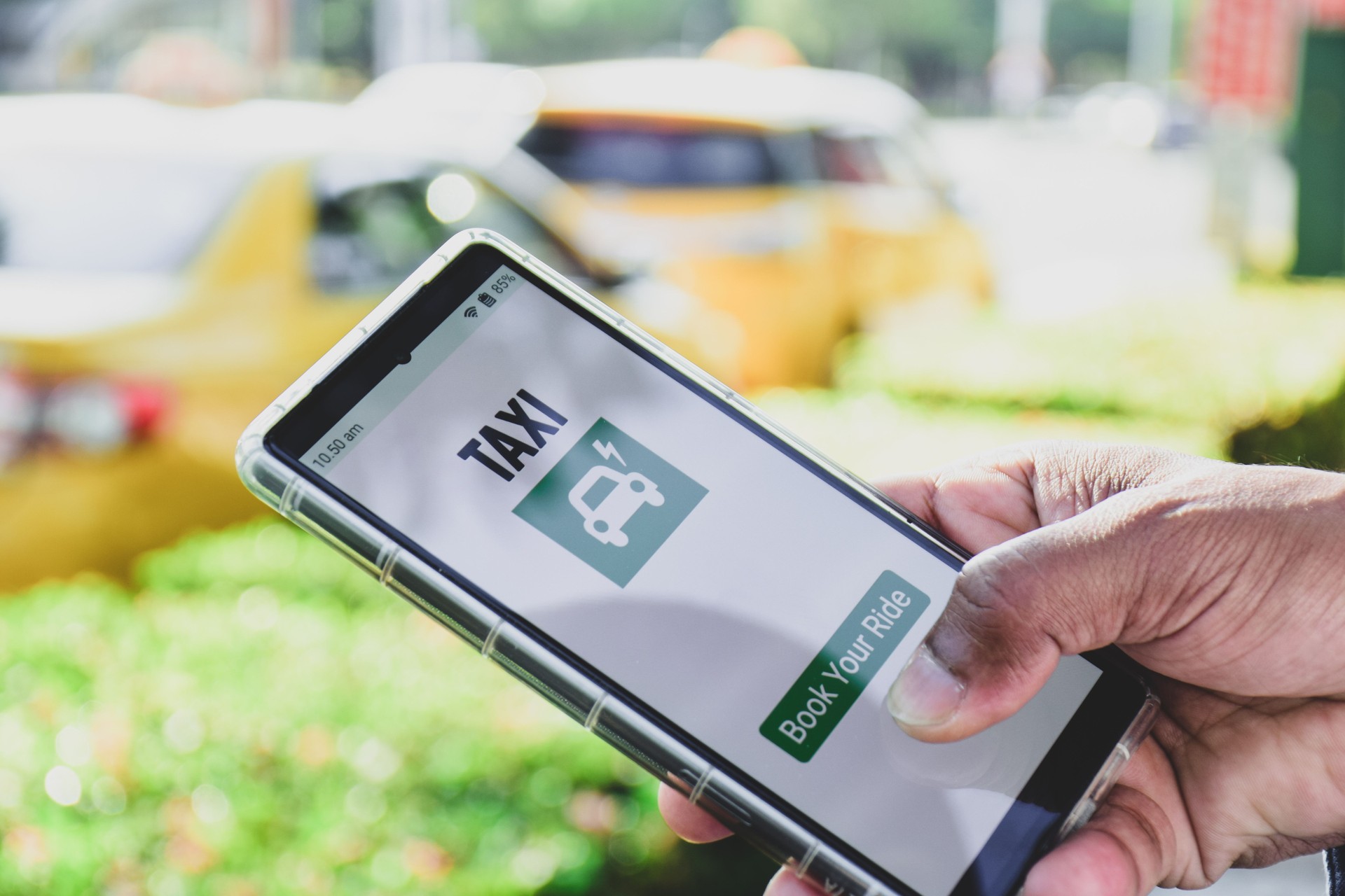 Person using a booking app for electric taxi cab to reach his destination. Selective focus on the device screen, zero carbon emissions, eco friendly transportation concept.